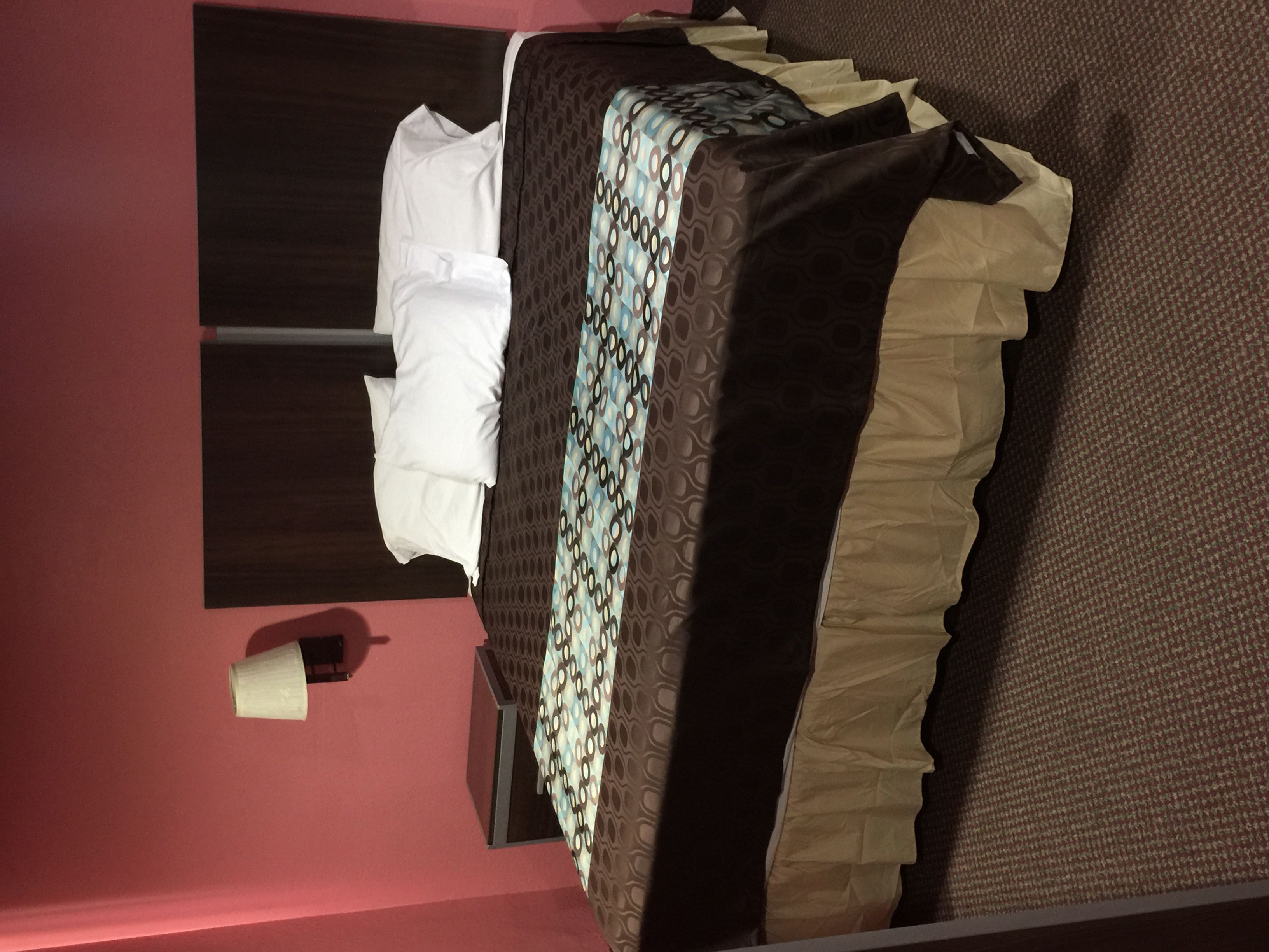 Habitació d'hotel amb un llit, una vetustat, un mirall i una paret vermella.