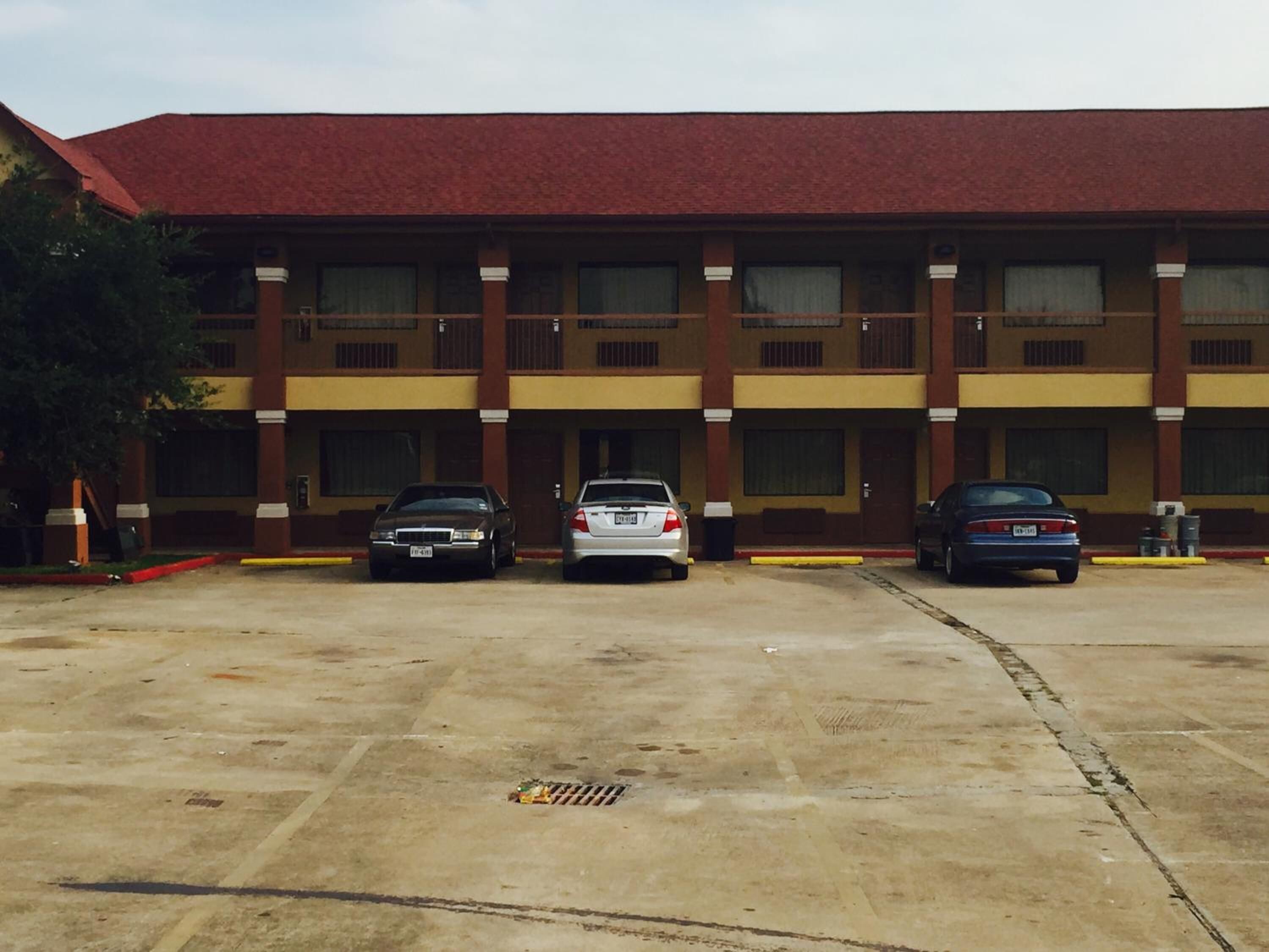 A multi-story building with a red roof and a parking lot with three cars.