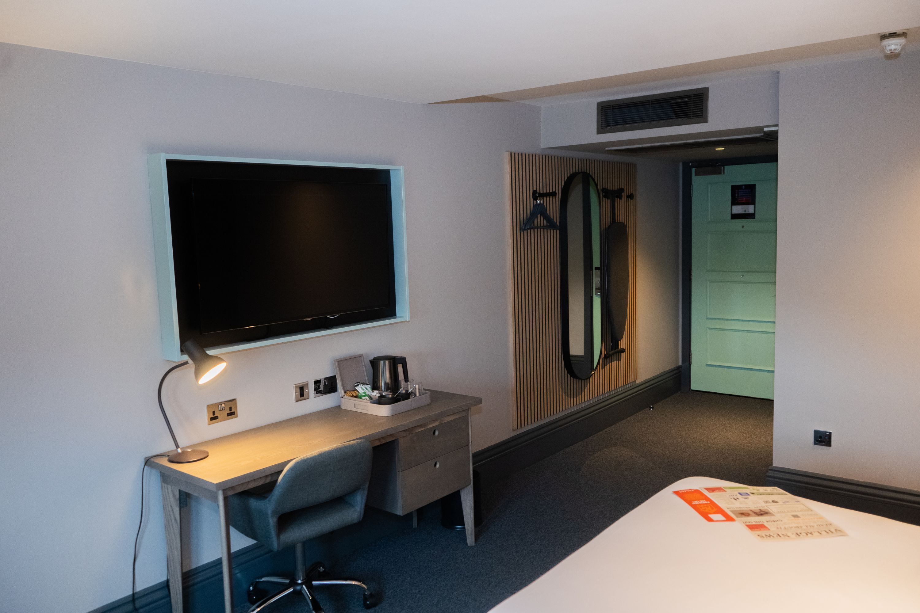 Una habitación de hotel con cama, escritorio con ordenador, televisor y armario.