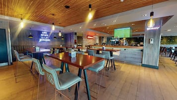 A modern restaurant with wooden ceiling and bar area, seating arrangements, and a neon sign.