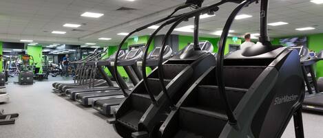 A gym with multiple treadmills, exercise equipment, and green walls.