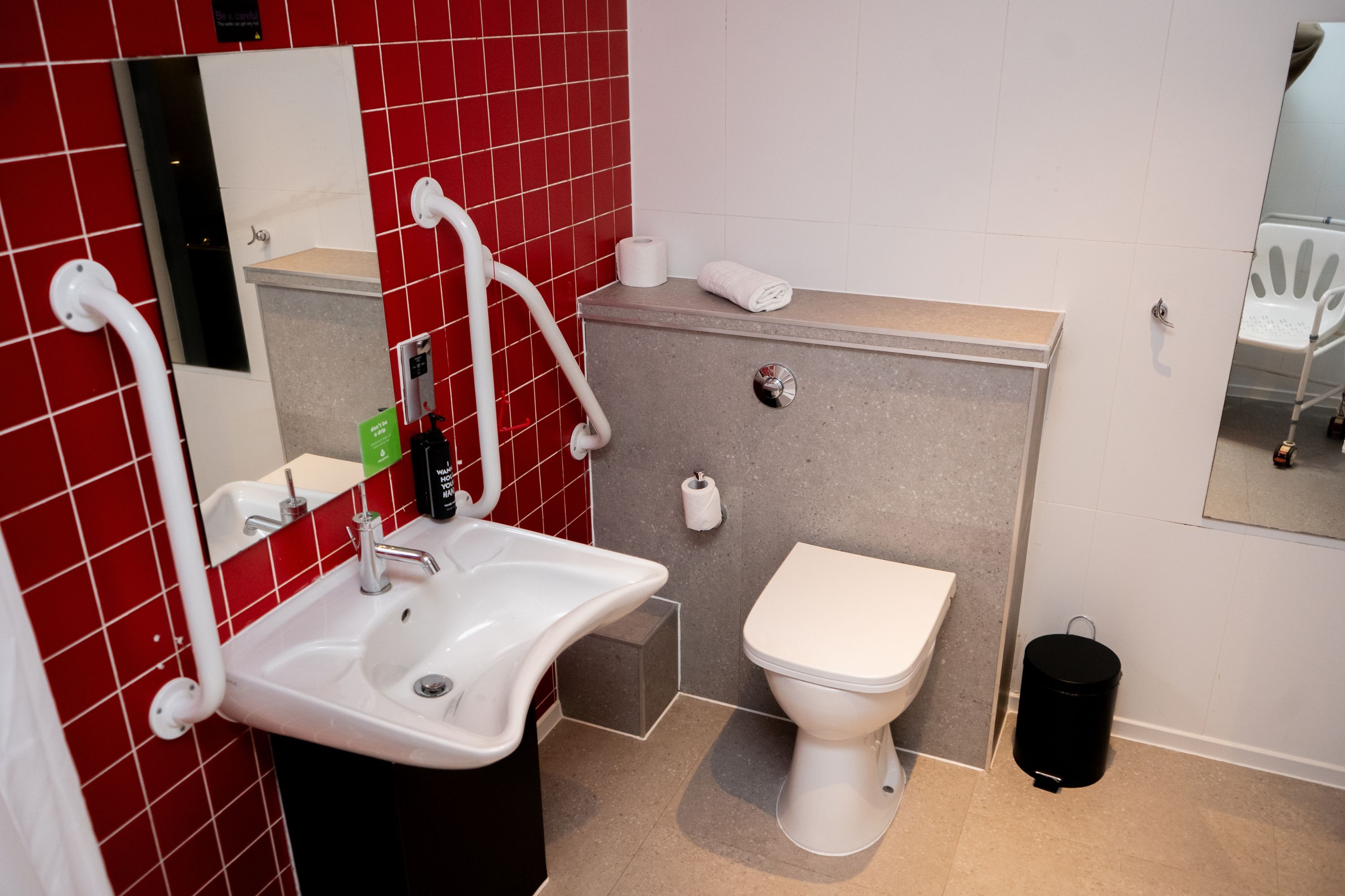 A modern bathroom with a white sink, a toilet, and a mirror.
