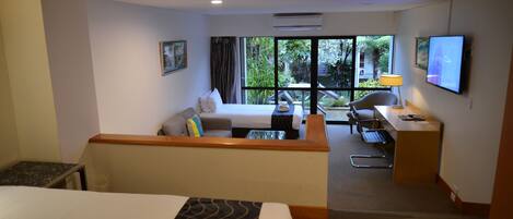 A hotel room with a bed, a sofa, a desk, and a TV.