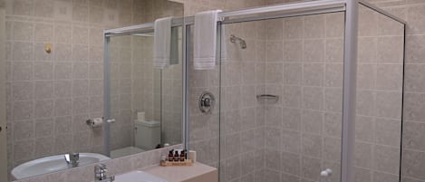 A bathroom with a sink, mirror, and shower.