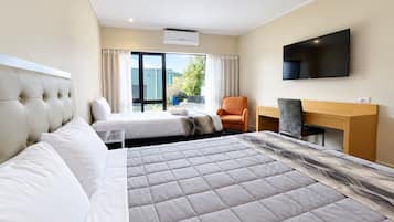 Een hotelkamer met een bed, een bureau, een stoel, een televisie en een raam met gordijnen.
