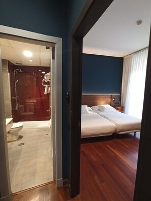 A hotel room with a shower area, a bed, and a nightstand. - Hotel Spa Paris (León)