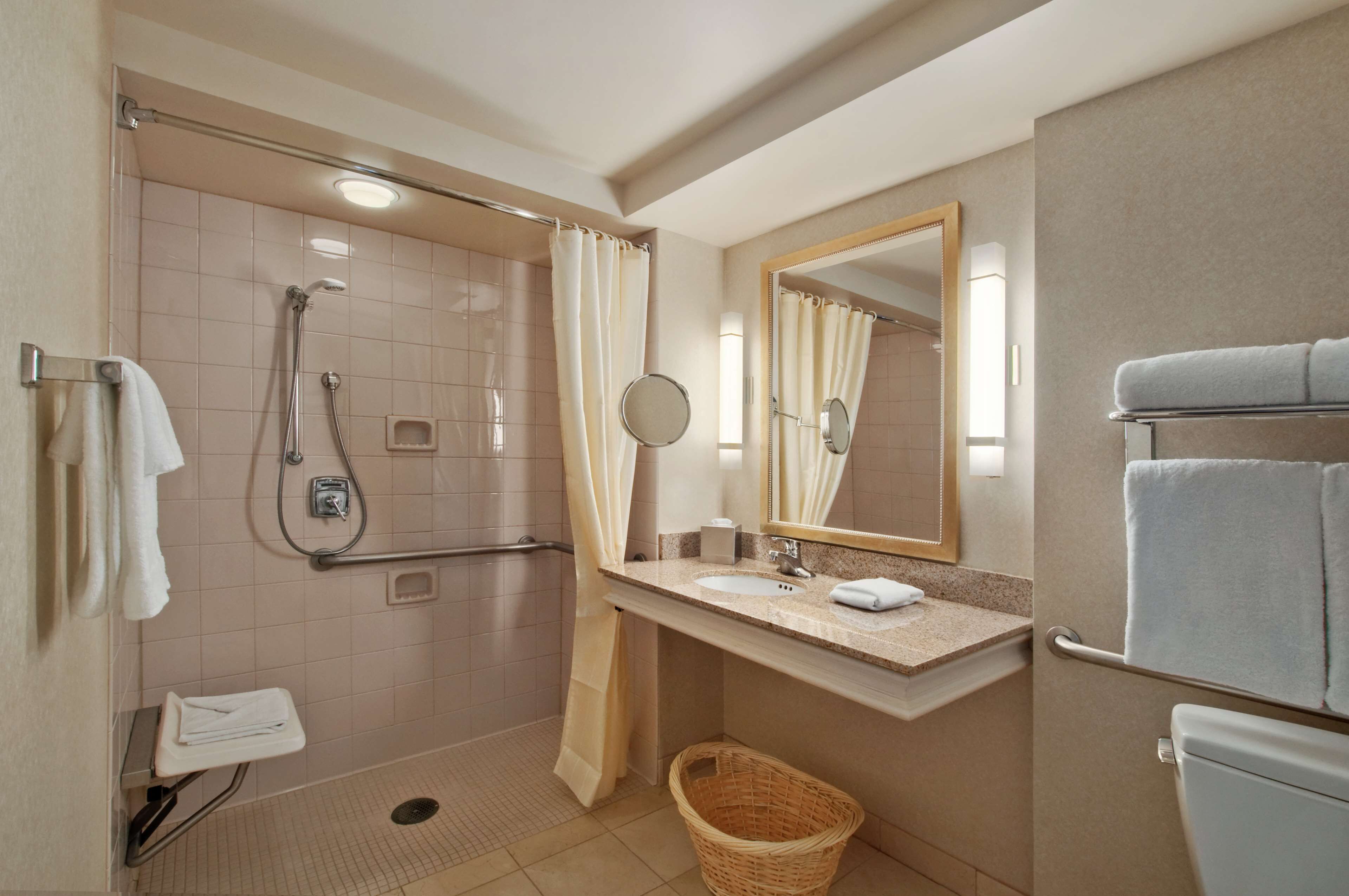 A bathroom with a shower, toilet, sink, and a mirror.
