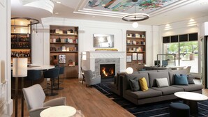 Un hall d’hôtel moderne doté d’une cheminée, d’espaces de détente, de bibliothèques et d’un bar.