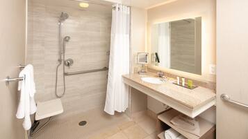 Un baño moderno con ducha, lavamanos y espejo.