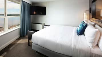 A hotel room with a large bed, a desk, a flat-screen TV, and a view of the outdoors.