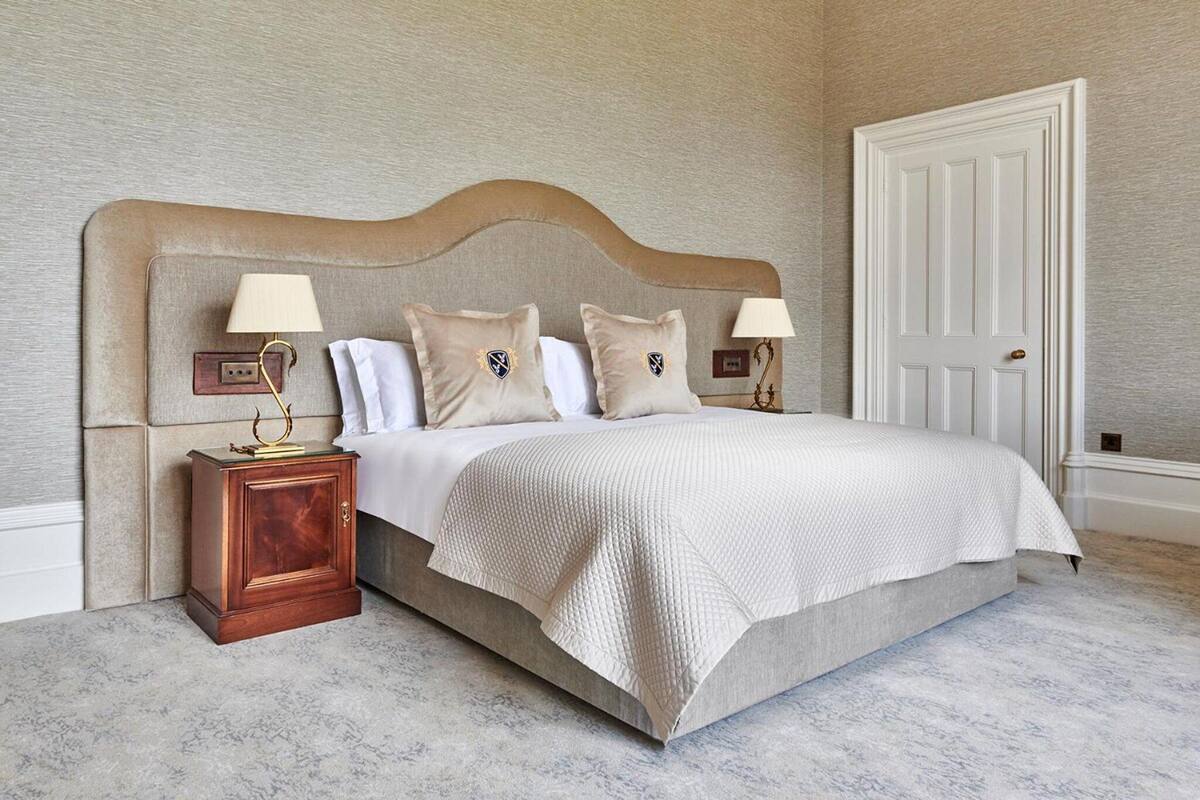 A neatly arranged bedroom with a large bed, two bedside tables with lamps, and a door.