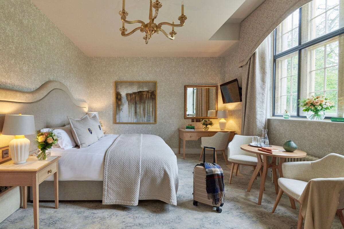 A hotel room with a bed, desk, chair, and a window with a view.