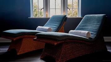Relax in a serene spa room with two massage chairs, each equipped with a towel, set amidst a calming atmosphere.