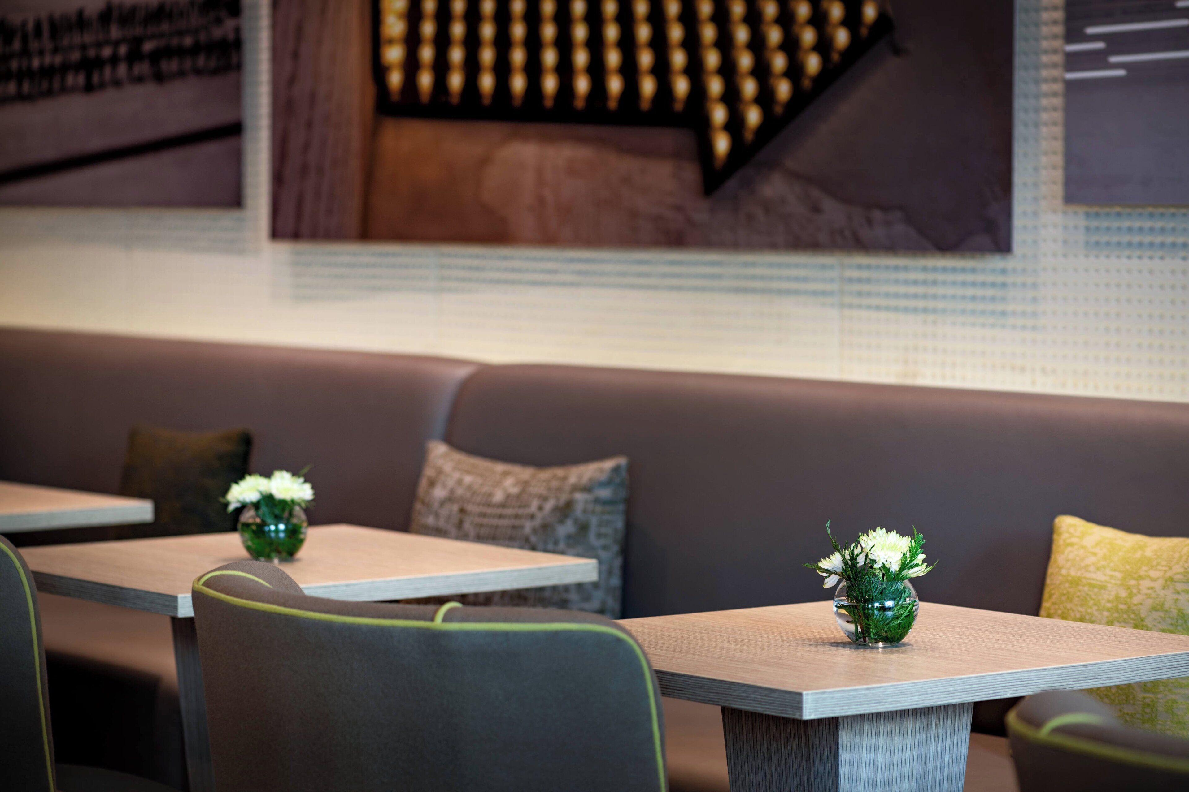 A modern restaurant interior with a wooden table and a cushioned bench.