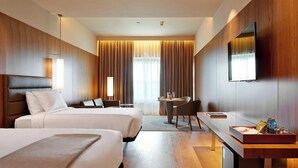 A hotel room with two beds, a desk, a chair, a TV, and a large window with curtains. - AC Hotel Diagonal L'Illa by Marriott (Barcelona)