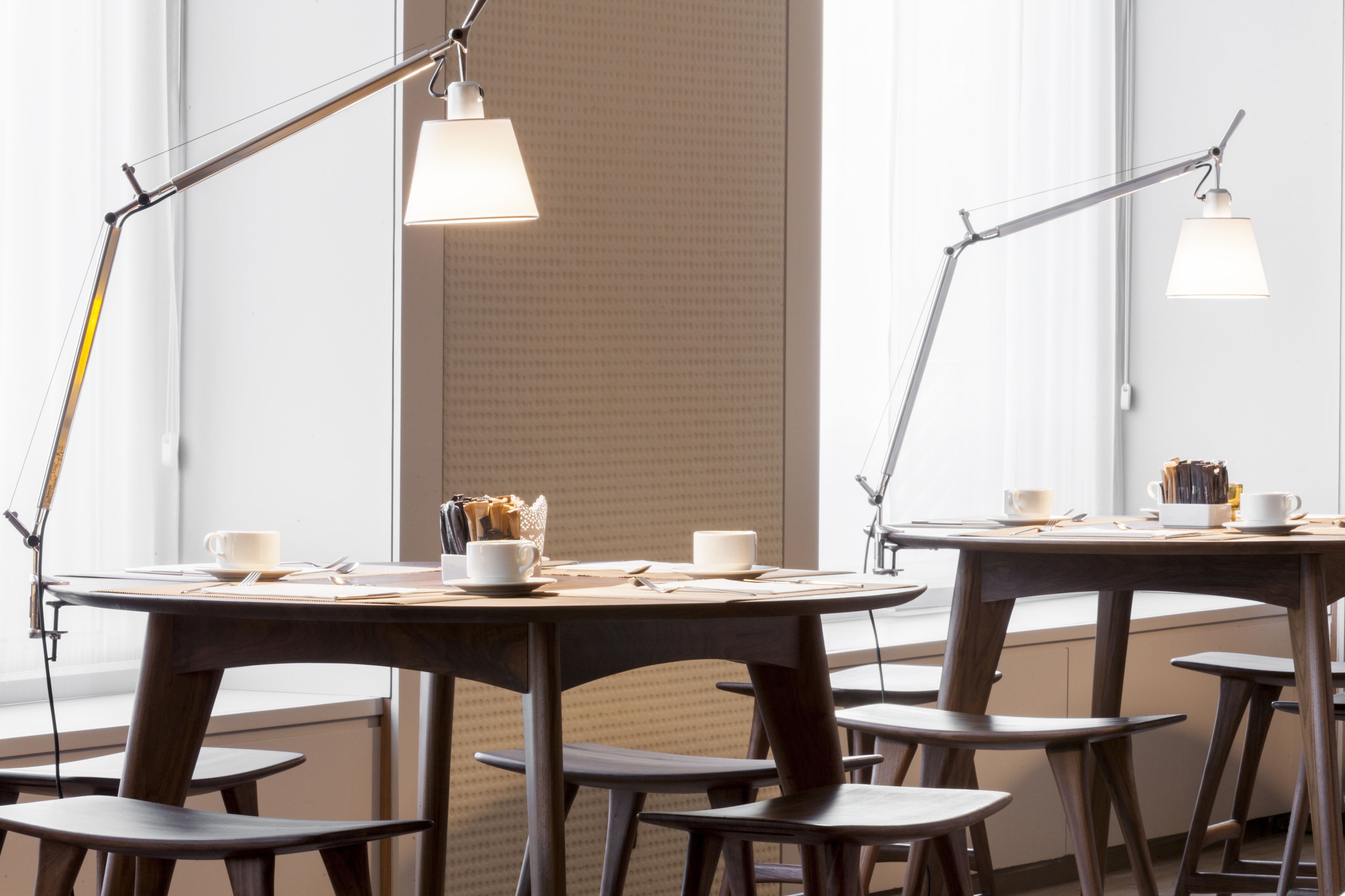 Un comedor moderno con mesas redondas y sillas a juego, equipado con lámparas colgantes y tazas de café.