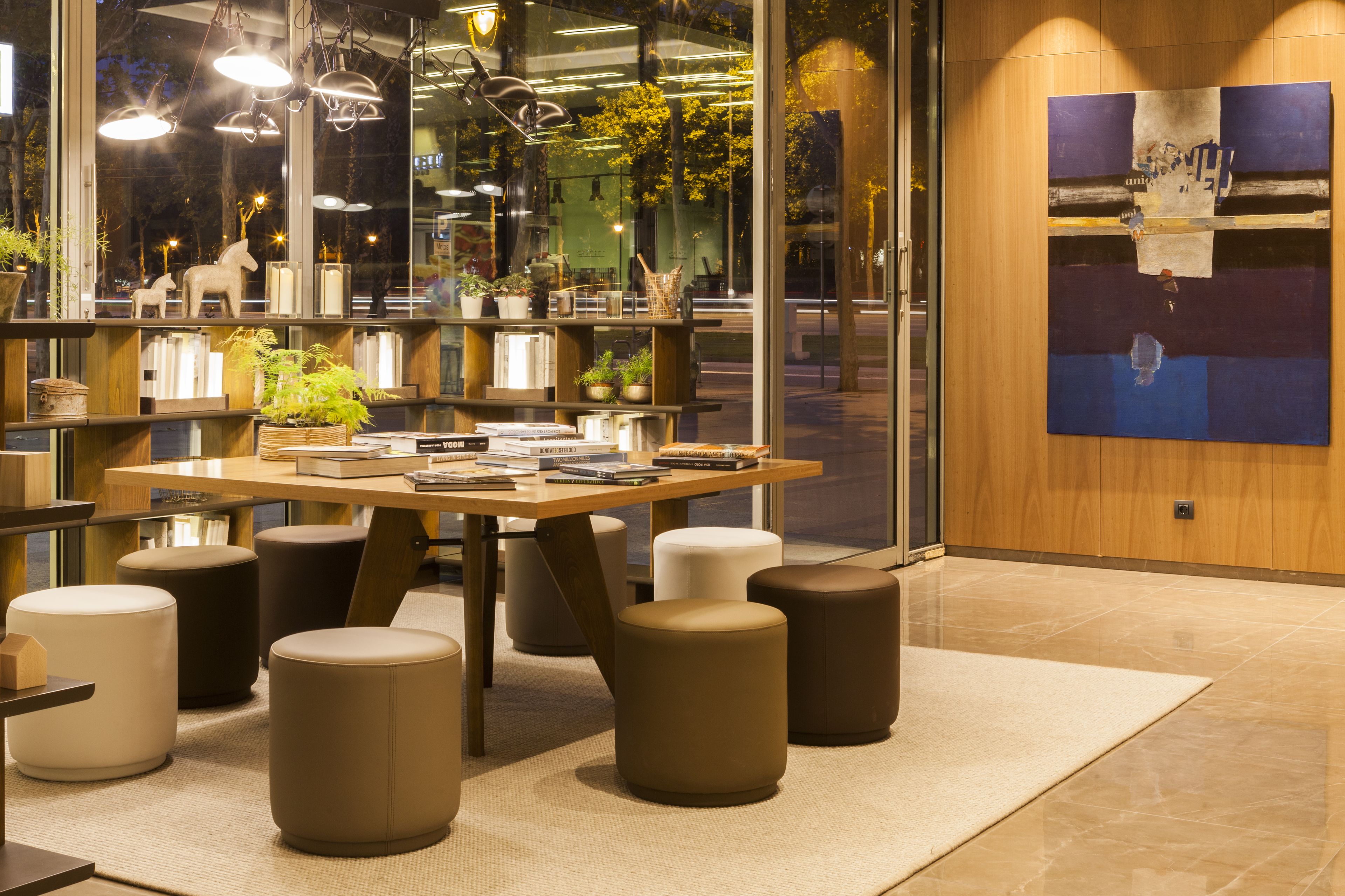 A modern interior with a wooden table, multiple seating options, and a large window with plants.