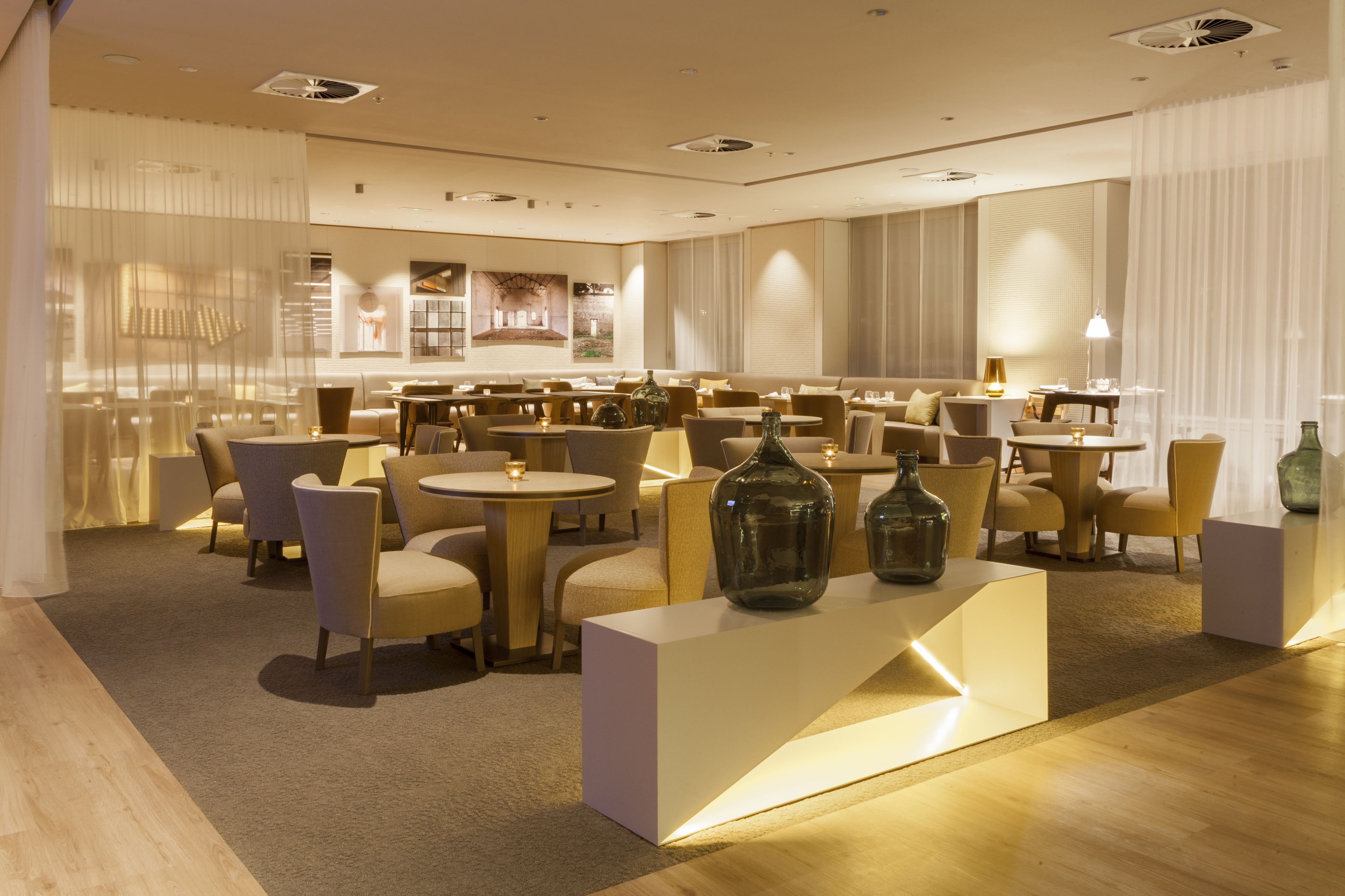 A modern hotel lobby with round tables, comfortable seating, and decorative vases.