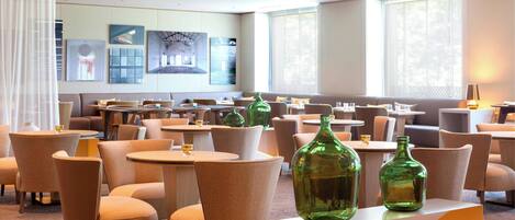 A hotel lobby with multiple seating areas, tables, and artwork on the walls.
