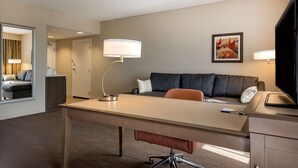 Ein Hotelzimmer mit Schreibtisch, einer Couch, einem Fernseher und einer Lampe.
