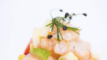 Primer plano de un plato de mariscos con camarones, verduras picadas y guarniciones.