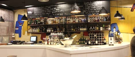 A bar with a white counter, multiple stools, and shelves stocked with bottles.