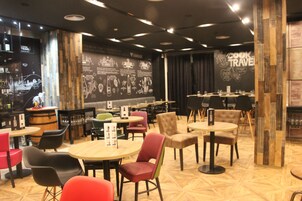 A restaurant with round tables and chairs, a bar area, and a wall with text and graphics.