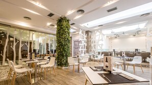 Un restaurante moderno con suelo de madera, sillas blancas y una planta verde en el centro.