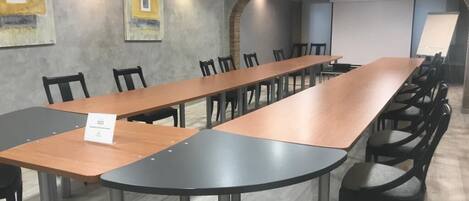 A conference room with a long table and chairs, a whiteboard, and a projector screen.