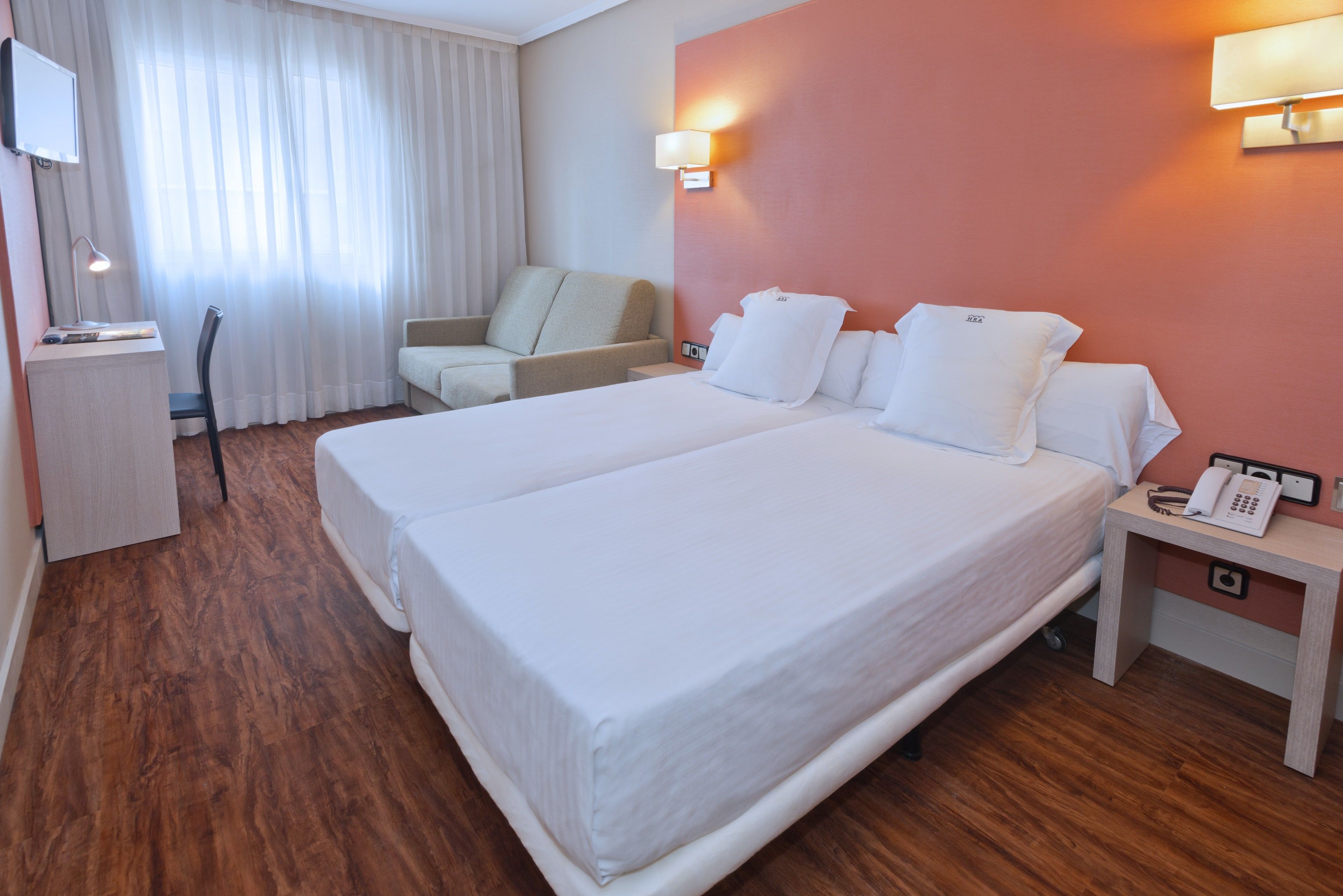 Une chambre d’hôtel avec un grand lit, un bureau, une chaise et une table de chevet avec un téléphone.