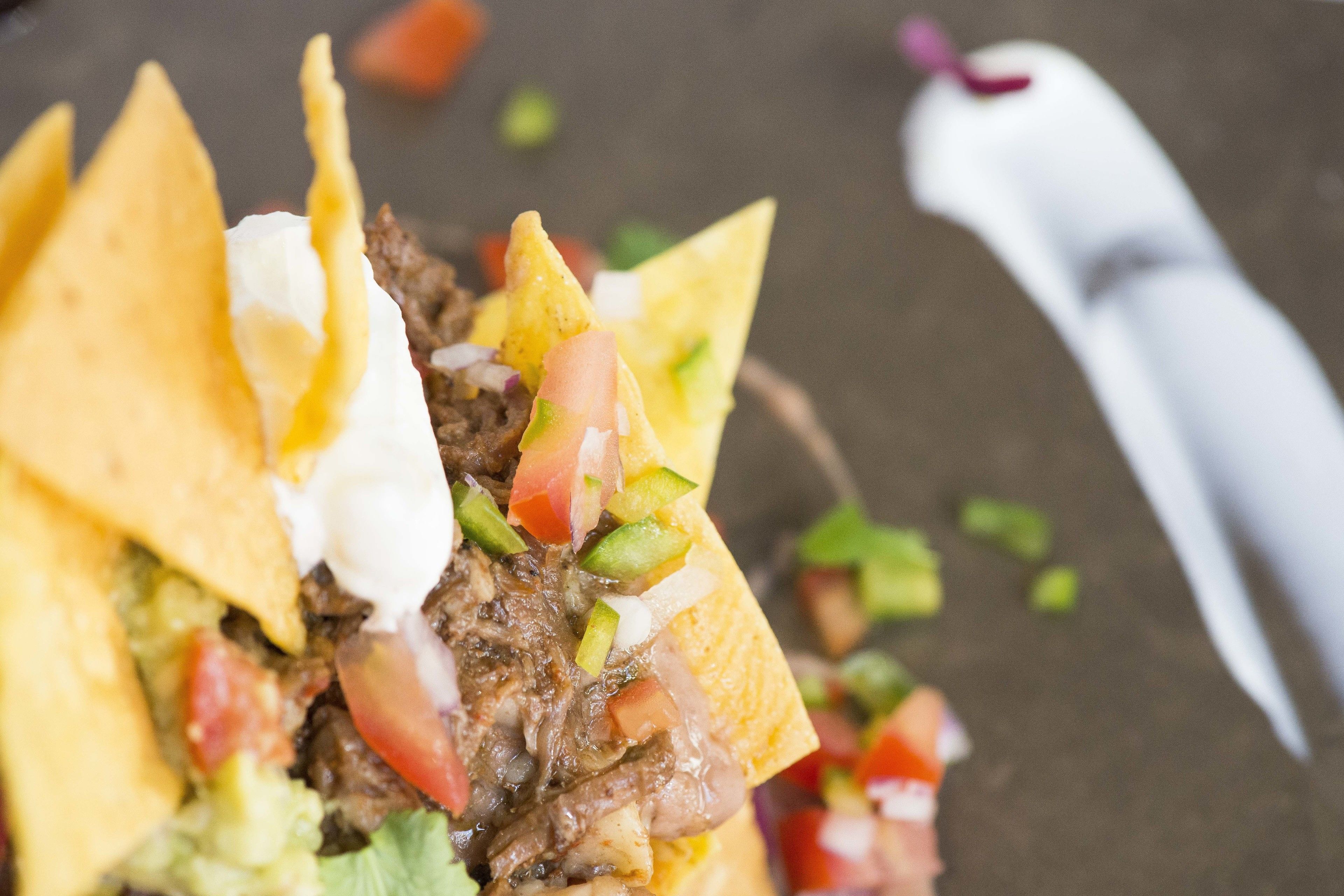 Primer plano de un plato de nachos con carne, queso y verduras.