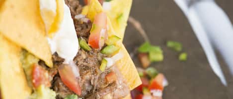 Primer plano de un plato de nachos con carne, queso y verduras.