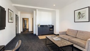 A modern living room with a sofa, coffee table, and a kitchen area in the background.