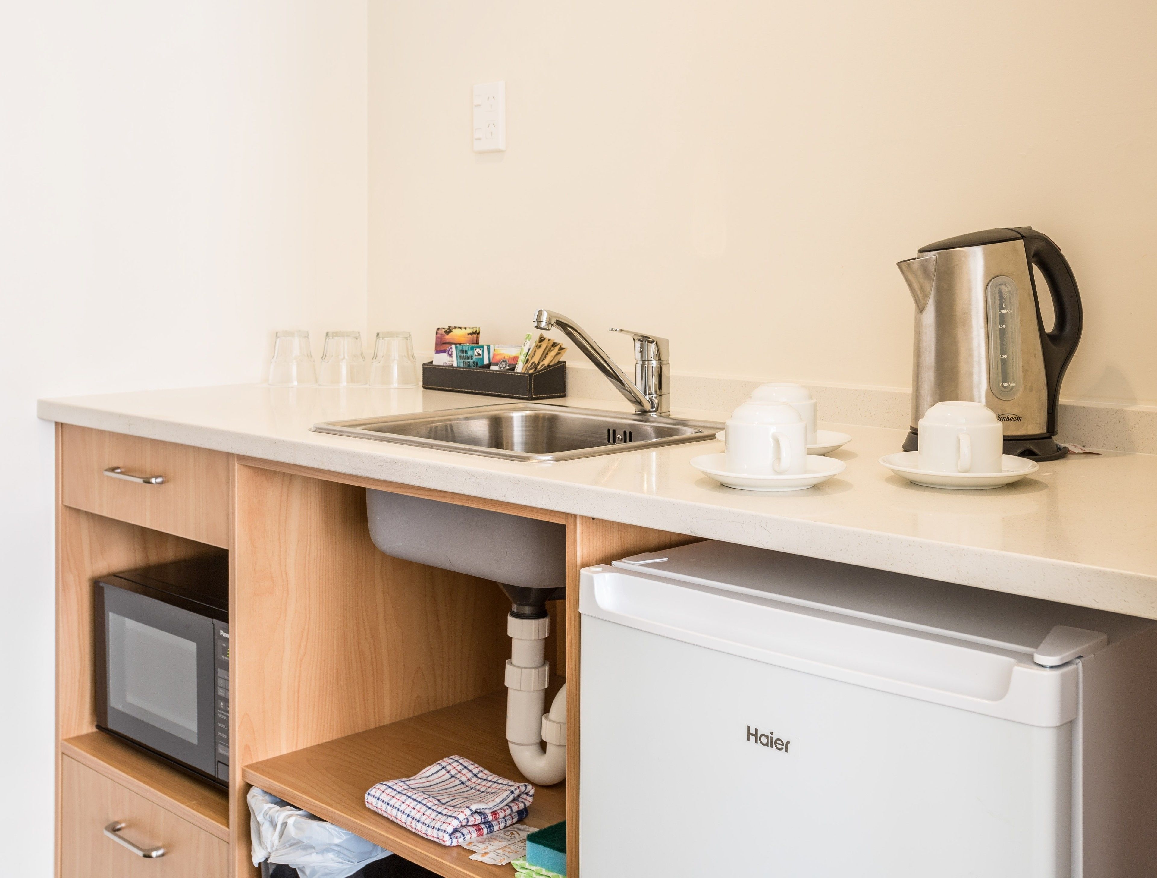 A compact kitchenette with a sink, a coffee maker, and a microwave.