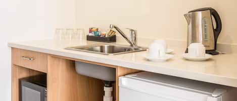 A compact kitchenette with a sink, a coffee maker, and a microwave.