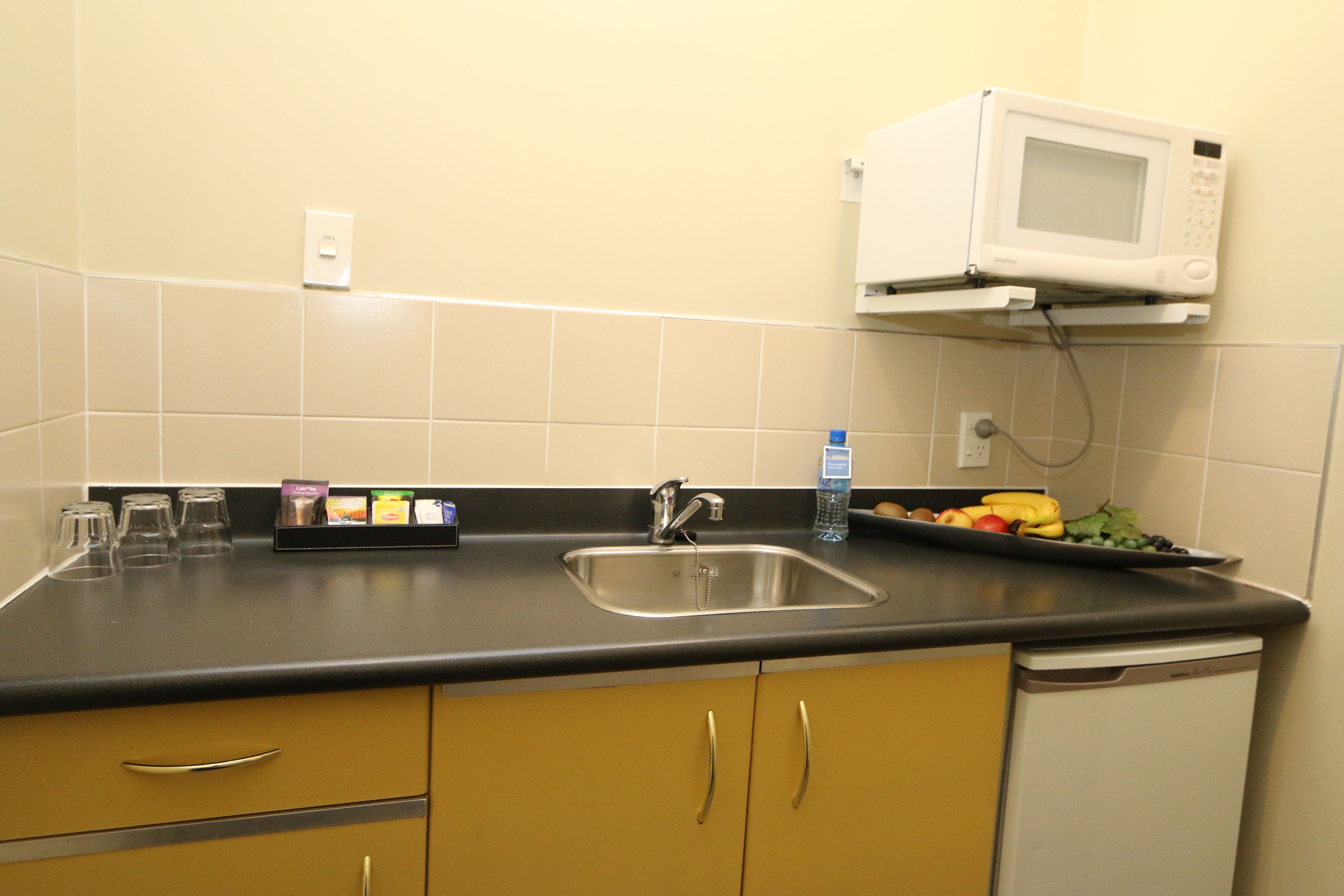 A kitchen with a microwave, sink, and cabinets.