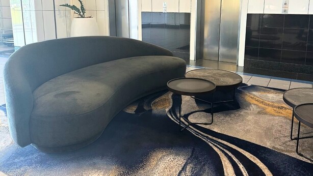 A modern lobby with a grey sofa, a small round table, and two elevators.