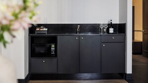 A modern kitchen with a built-in microwave, a wine bottle, and glasses on the counter.