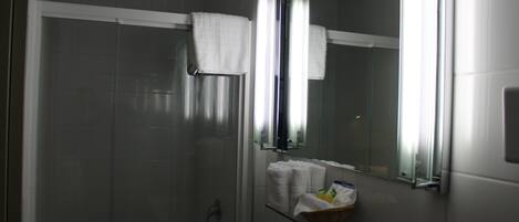A modern bathroom with a glass shower enclosure, a white sink, and a mirror with a towel rack.