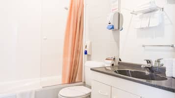 Un baño con bañera, inodoro, lavamanos y toallero.