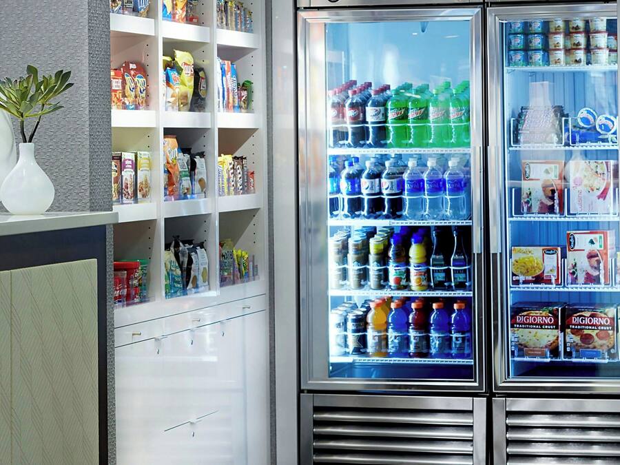 A vending machine area with snack and drink options, a refrigerated section with beverages, and a small plant on the counter.