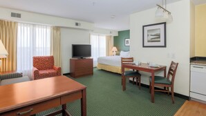 A hotel room with a bed, a TV, a desk with chairs, a lamp, and a framed picture on the wall. - Residence Inn by Marriott Oklahoma City South (Oklahoma City)