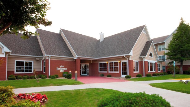 A two-story brick building with a red roof, a central entrance, and a landscaped front yard with flower beds. - Residence Inn by Marriott Oklahoma City South (Oklahoma City)