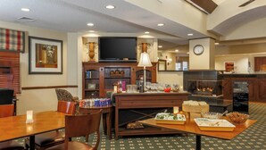 A dining area with a wooden table, chairs, a fireplace, and a television. - Residence Inn by Marriott Oklahoma City South (Oklahoma City)