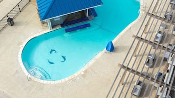 Vista aérea de una piscina con una estructura de techo azul, sillas de descanso y un pequeño jacuzzi.