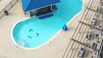 A swimming pool with a blue roof structure, a diving board, and a small circular hot tub.