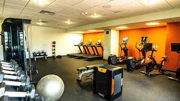 Une salle de sport équipée de tapis de course, de vélos elliptiques et de matériel de musculation.