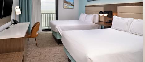 A hotel room with two beds, a desk, a chair, a TV, and a balcony with a view.