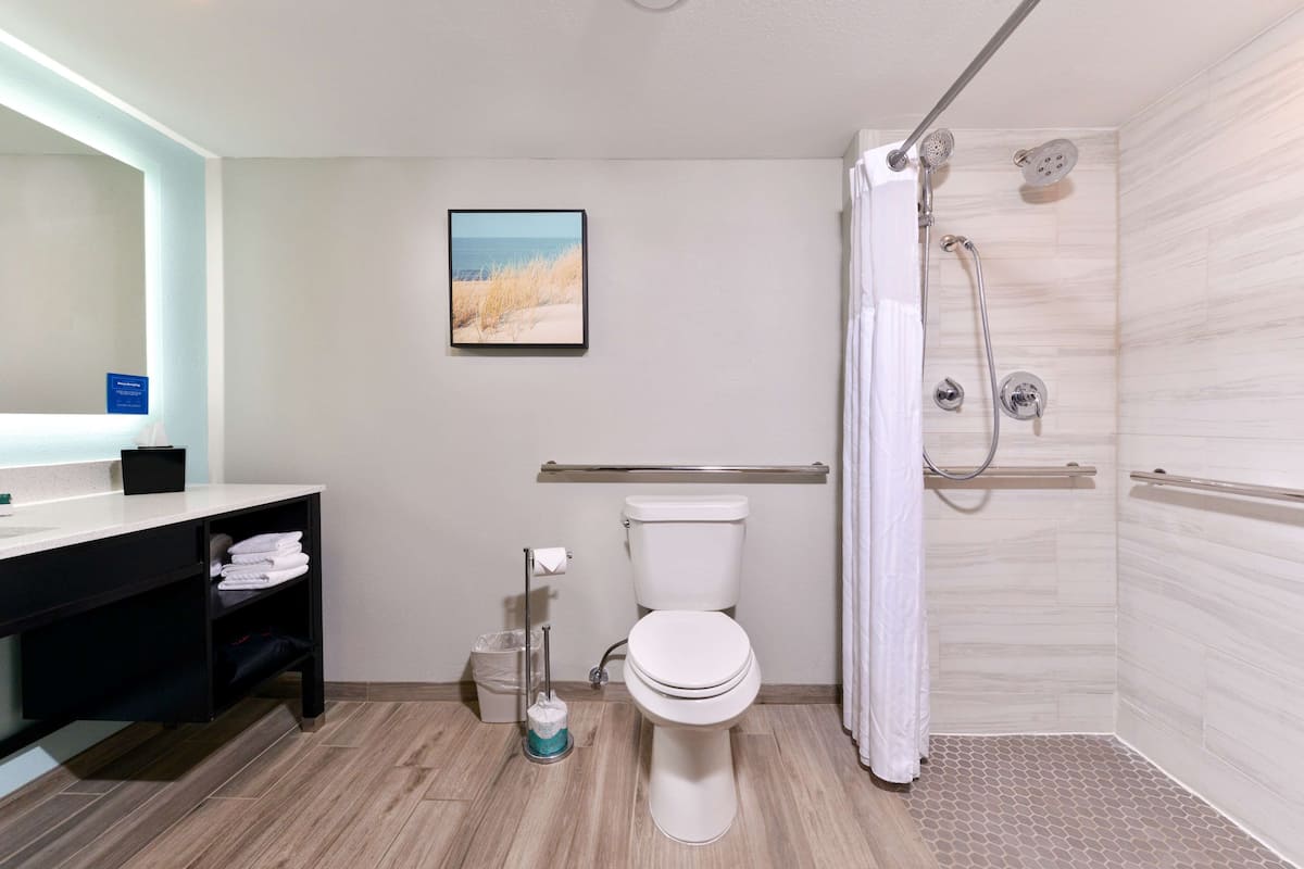 A modern bathroom with a toilet, shower, and sink.