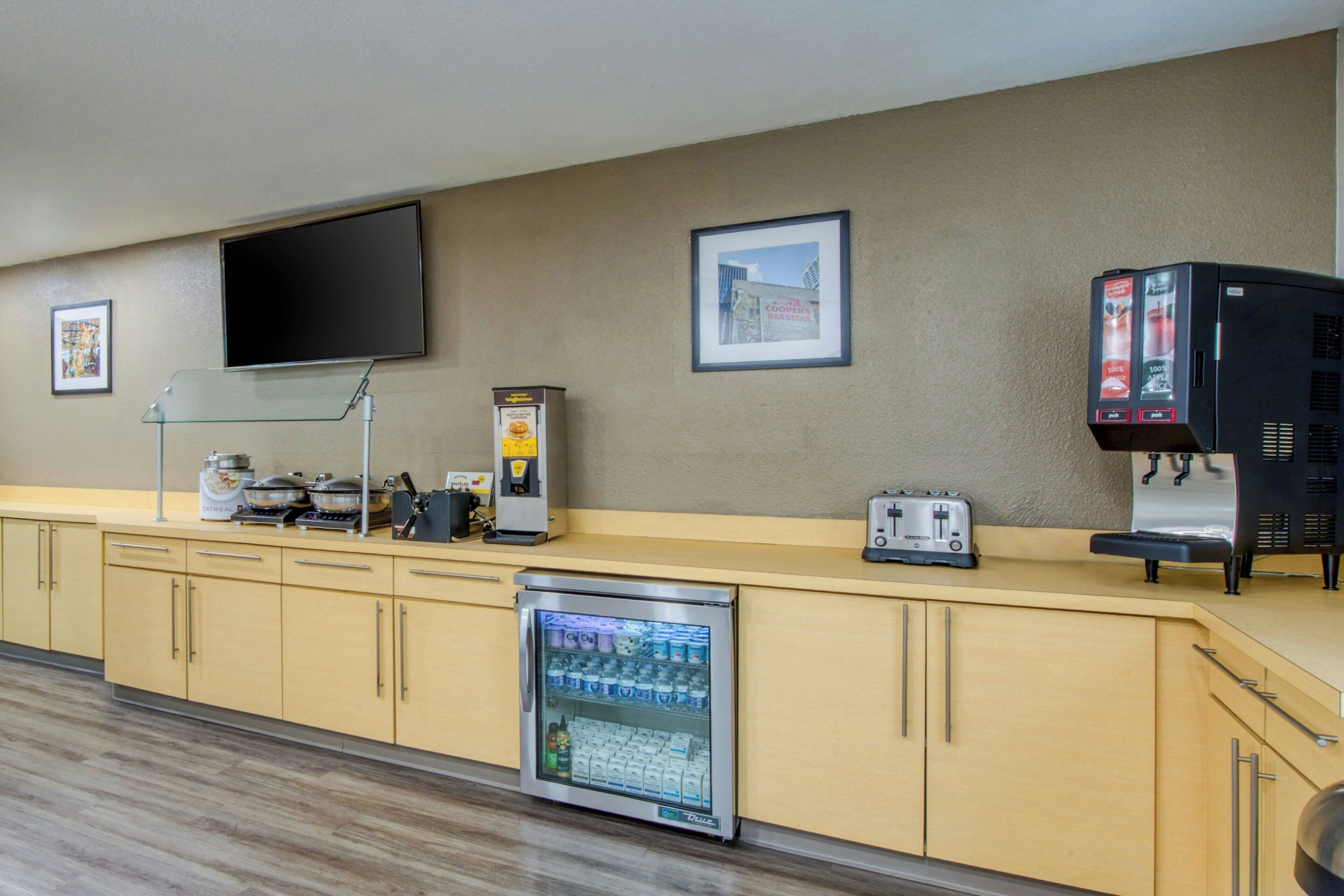A kitchenette with a refrigerator, microwave, toaster, and coffee machine.
